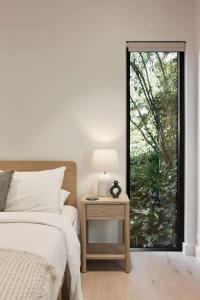a bedroom with a bed and a table with a lamp at Treetop House in Crafers