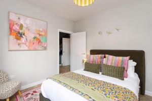 a bedroom with a large white bed with colorful pillows at Paradykes House in Loanhead