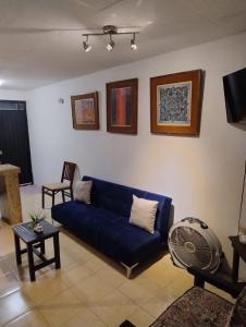 a living room with a blue couch and a fan at Bungalow Turrent, a 5 minutos de Playa Mocambo in Veracruz