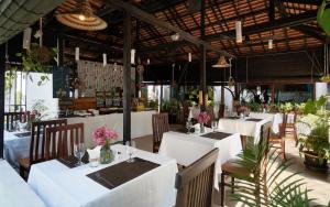 a restaurant with white tables and chairs and plants at Harmony Indochine d'Angkor in Siem Reap