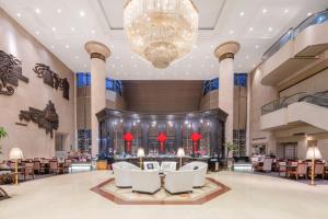 a lobby of a hotel with white chairs and a chandelier at Shanghai Qilu Hotel in Shanghai