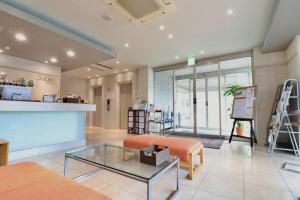 a living room with a glass table and orange chairs at ホテルクオーレ敦賀 男性専用の大浴場サウナをご用意 in Tsuruga