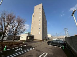 a car parked in a parking lot in front of a building at ホテルクオーレ敦賀 男性専用の大浴場サウナをご用意 in Tsuruga