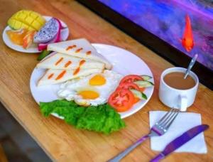 a plate of food with eggs and tomatoes and a cup of coffee at Phương Phương 2 Hotel in Hà Tĩnh