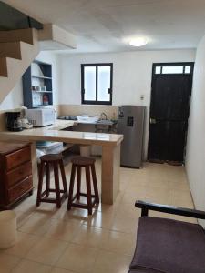 a kitchen with a counter and two stools in it at Bungalow Turrent, a 5 minutos de Playa Mocambo in Veracruz