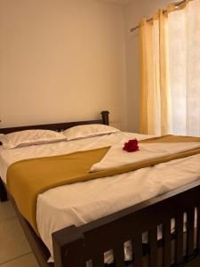 a bed with a yellow blanket and a red rose on it at Florence Stays Munnar in Munnar