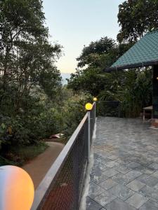 a fence next to a walkway with trees and a building at Florence Stays Munnar in Munnar +5 photos