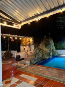 a swimming pool with a large rock next to a house at Finca Turística VILLA NELLA in Acacías