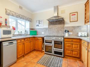 a kitchen with wooden cabinets and a stove top oven at Halls Bank Farm in Plumbland +19 photos