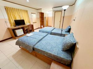 a hotel room with two beds and a television at เพิ่มพูนแมนชั่น พิษณุโลก Phoempun Mansion in Sathani Phitsanulok