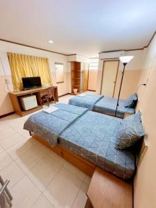 two beds in a room with a desk and a television at เพิ่มพูนแมนชั่น พิษณุโลก Phoempun Mansion in Sathani Phitsanulok