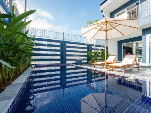 a swimming pool with an umbrella and two chairs and avisor at Shadyside 4B in Tân Thành (1)