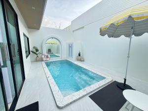 a swimming pool in a house with an umbrella at Mermayda pool villa hatyai -เมอเมดา in Hat Yai