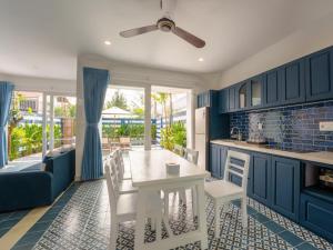 a kitchen with blue cabinets and a white table and chairs at Shadyside 4B in Tân Thành (1)