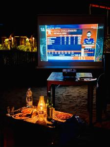a television screen with a table with food and a table with a table sidx sidx at Taya Beach Front in Gokarna