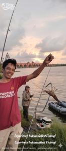 a man holding a fishing rod in the water at Kopinka in Yogyakarta
