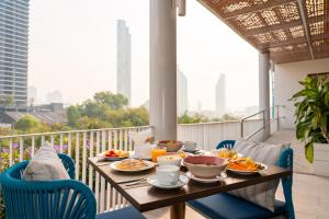 a table with plates of food on a balcony at Away Bangkok Riverside Kene in Bangkok