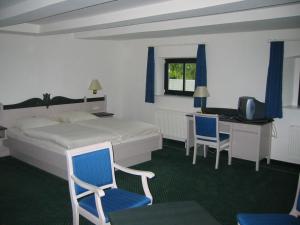 a bedroom with a bed and a desk with a computer at Gutshaus Redewisch Hotel & Restaurant in Boltenhagen