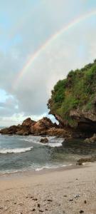 a rainbow over a beach with the ocean at Kopinka in Yogyakarta