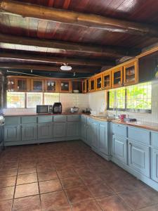 a large kitchen with blue cabinets and windows at Cabaña Brisa Del Río in Cooper