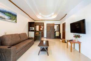 a living room with a couch and a flat screen tv at The Green Beach Resort in Sam Roi Yot