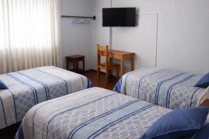a hotel room with two beds and a television at Hostal Arias in Oxapampa