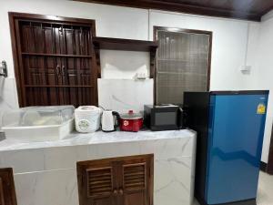 a kitchen with a microwave and a blue refrigerator at Mary's House Xiengthong in Luang Prabang +4 photos