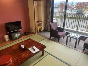 a living room with a tv and a large window at Hotel Kadoman in Aso