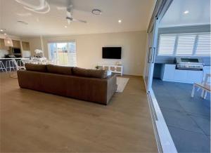 a living room with a brown couch and a tv at Capri Waterfront Resort-Style 5BR & Pool in Gold Coast