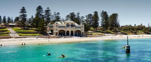 people on surfboards in the water in front of a beach at Beach House Perth in Perth