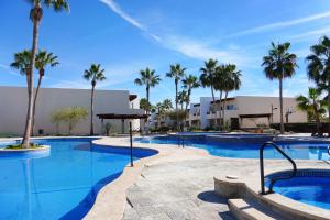 a swimming pool with palm trees in a resort at Beach, Please MX in Puerto Peñasco