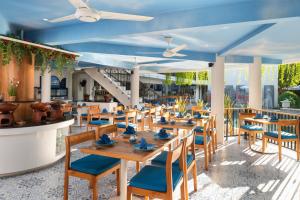 a restaurant with wooden tables and blue chairs at Away Bali Legian Camakila in Legian