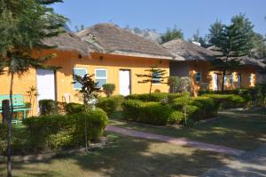 a yellow house with bushes in front of it at Kangs Nirvana Resorts and Spa in Hoshiārpur