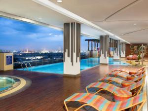 a hotel lobby with a swimming pool and chairs at Aston Gresik Hotel & Conference Center in Gresik