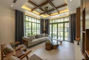 a living room with a couch and some windows at Hana Village Garden Tropical Bãi Khem in Phú Quốc