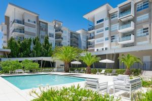 an apartment building with a swimming pool and palm trees at Boulevard North Lakes in North Lakes +7 photos