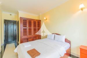 a bedroom with a white bed with a brown towel on it at Serey Sok San Apartment in Phumi Ta Phul