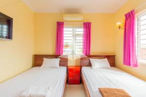 two beds in a room with pink curtains at Serey Sok San Apartment in Phumi Ta Phul +2 photos