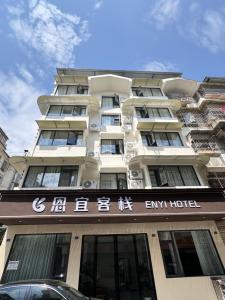 a tall white building with a hotel sign in front of it at 恩宜客栈 in Dujiangyan +26 photos