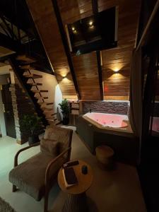 a bathroom with a bath tub and a chair and a tub at Luxury AFrame with Private Jacuzzi Poás Volcano in Vara Blanca