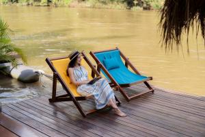 a woman sitting in a chair on a dock at The Float House River Kwai in Sai Yok
