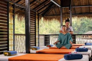 a man and a woman sitting on beds in a room at The Float House River Kwai in Sai Yok
