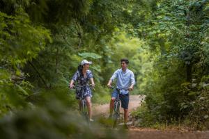a man and a woman riding bikes down a dirt road at The Float House River Kwai in Sai Yok