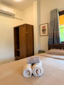 a pair of towels sitting on top of a bed at Baan Yanikar in Lampang