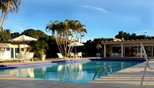 a swimming pool with chairs and umbrellas next to a house at Hotel Pousada Lord in Teixeira de Freitas