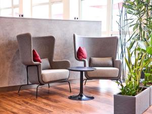 two chairs and a table in a waiting room at ibis Hotel Düsseldorf Hauptbahnhof in Düsseldorf
