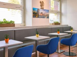 a restaurant with four tables and blue chairs at ibis Hotel Düsseldorf Hauptbahnhof in Düsseldorf