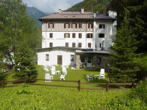 um grande edifício branco com cadeiras brancas num campo em Hotel Europa em Peio Fonti