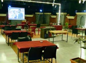 a restaurant with tables and chairs and a projection screen at Hotel Kinara Lodge in Jāmkhed