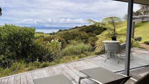 a patio with a table and chairs on a deck at Waiheke Luxury Blue and Green Rooms in Ostend
